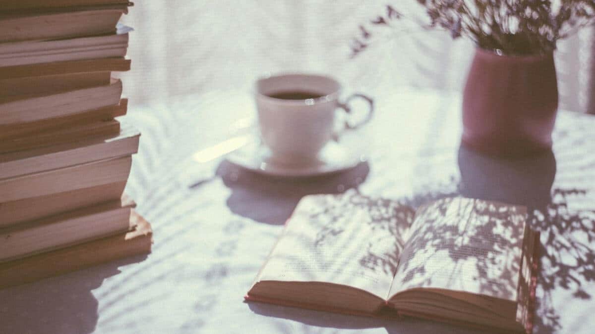 Image shows an open book and coffee cup in the background