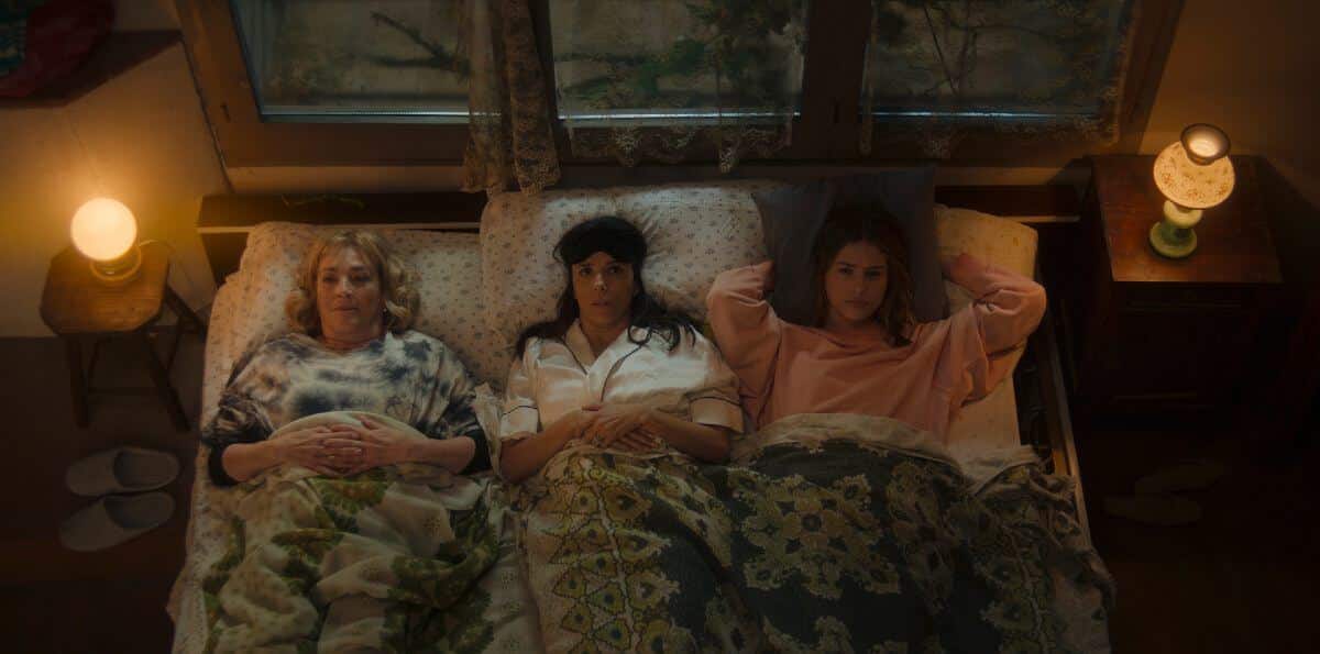 Three women lying in a bed looking at the ceiling.