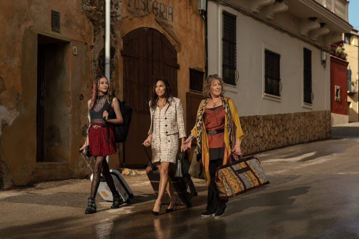 Land of Women Review featured image. The photo shows three women walking with luggage.