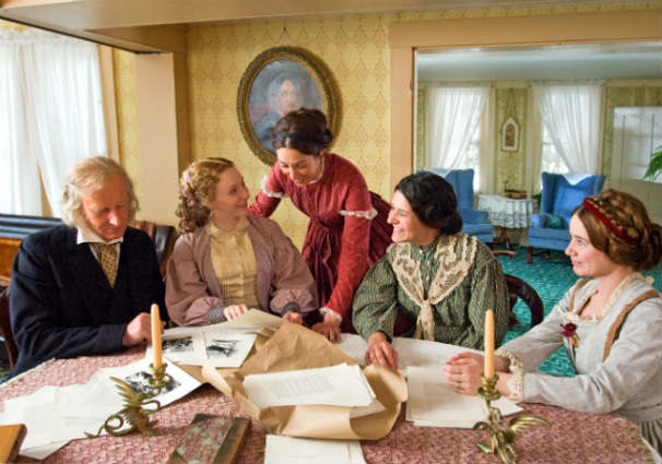 The Alcott family looks over the pages of Little Women in a scene filmed at Orchard House in Concord. Photo Credit: Liane Brandon