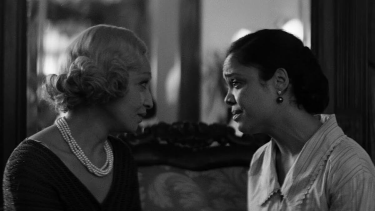 Passing Movie Review featured image. Ruth Negga and Tessa Thompson in Passing. They're talking on a couch.