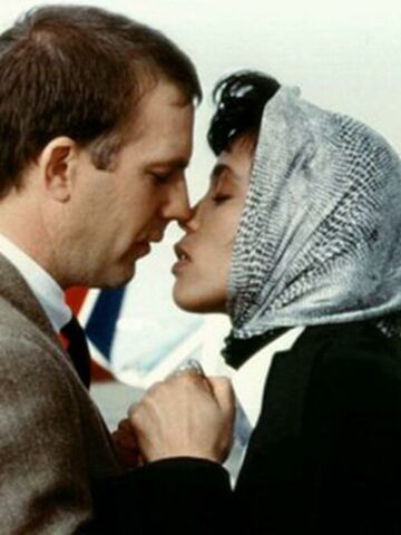 the bodyguard review featured image with Kevin Costner and Whitney Houston about to kiss.