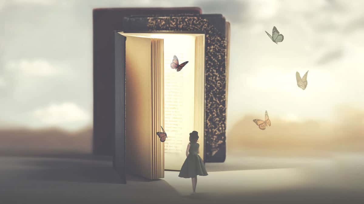 what is creativity and how to be creative featured image. The picture shows a woman standing in front of a lifesize book with butterflies.